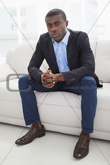 Serious businessman looking at camera on couch