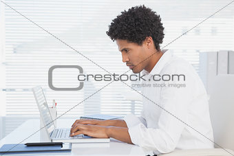Handsome casual businessman working on laptop