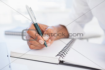 Businessman writing in notepad at desk