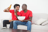 Football fans sitting on couch drinking beer