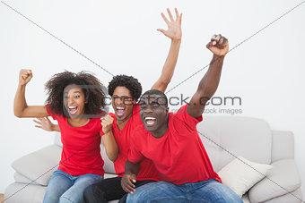 Football fans sitting on couch cheering together