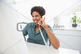 Handsome businessman talking on phone at desk