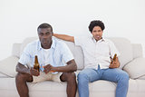 Football fans sitting on couch drinking beer