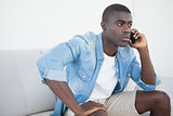 Casual man sitting on sofa on the phone