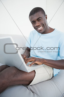 Casual man sitting on sofa using laptop