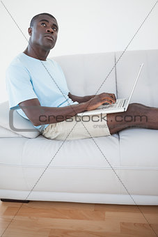 Casual man sitting on sofa using laptop
