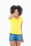 Pretty girl in yellow tshirt and denim hot pants pointing at camera