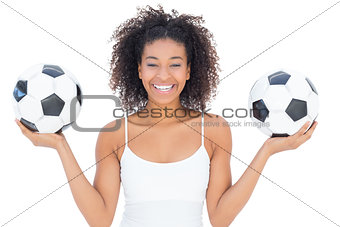 Pretty girl with afro hairstyle smiling at camera holding footballs