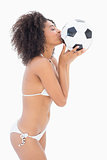 Athletic girl in white bikini kissing football