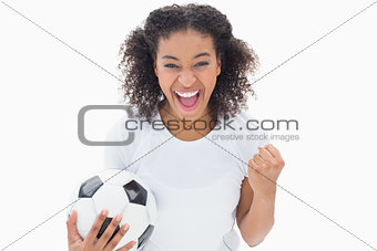 Pretty girl holding football and cheering at camera