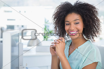 Casual businesswoman smiling at camera at her desk