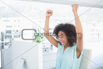 Casual businesswoman cheering at her desk