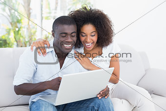 Attractive couple using laptop together on sofa