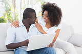 Attractive couple using laptop together on sofa