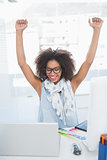 Pretty hipster cheering at her desk with laptop