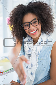 Pretty designer smiling at camera offering her hand