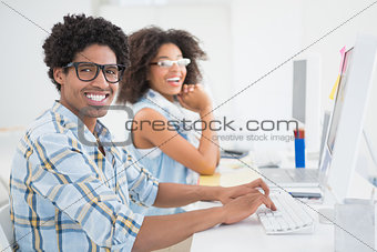 Happy design team smiling at camera working at desk