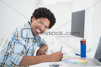 Young designer working at his desk smiling at camera