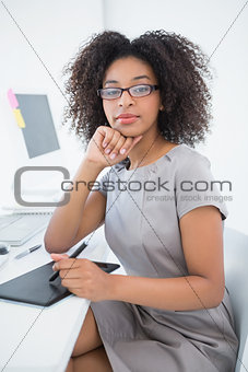 Young pretty designer smiling at camera at her desk