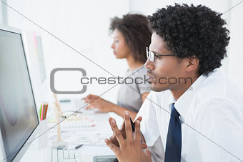 Young designer looking at computer at his desk