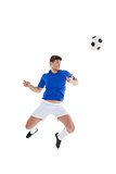 Football player in blue jersey jumping to ball