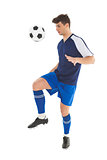 Football player in blue jersey kicking ball