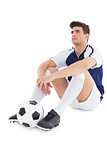 Football player sitting on the ground with ball