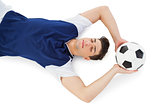 Football player lying on the ground with ball