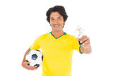 Football player in yellow holding winners trophy
