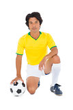 Football player in yellow kneeling with ball