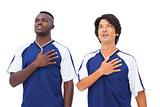 Football players in blue with hands on heart