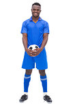 Football player in blue standing with ball