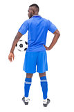 Football player in blue standing with ball