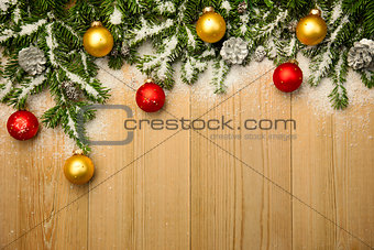 Christmas background with firtree and baubles on wood with snow