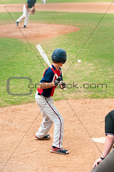 Teen player watching baseball at bat