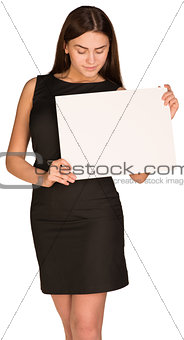 Businesswoman holding and looking at blank white sheet of paper