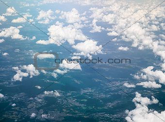 Ground and white fluffy clouds, aerial view from window of airplane