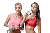 Two beautiful young women drinking water after fitness exercise