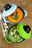 two kinds of cream soup (broccoli and pumpkin) in pot on wooden background