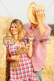 in love young couple on haystacks in cowboy hats