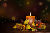 Autumn arrangement with candle against defocused holiday lights