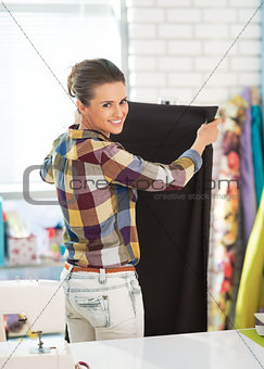 Portrait of happy tailor woman working with fabric in studio