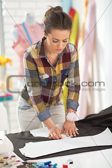 Happy tailor woman working with fabric in studio