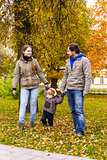 Young family walks with small son in autumn park