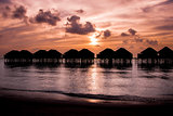 Maldives sunset with water villas silhouette