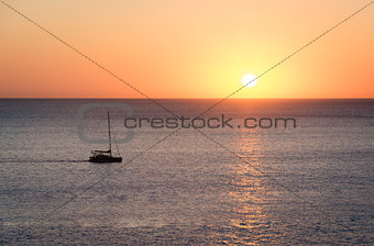 Sunset over sea with a sailboat