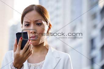 Portrait sad business woman typing sms phone street