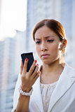Portrait sad business woman typing sms phone street