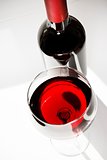 red wine glass near a bottle under daily light