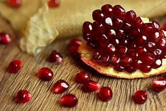 Raw pomegranate with seeds on wood